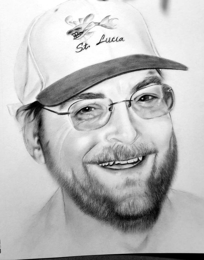 Graphite portrait of a smiling man in a St. Lucia cap